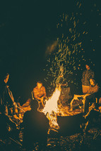 people sitting around a campfire at night 