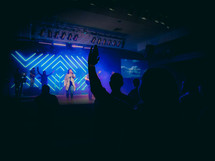 silhouettes of raised hands at a worship service 