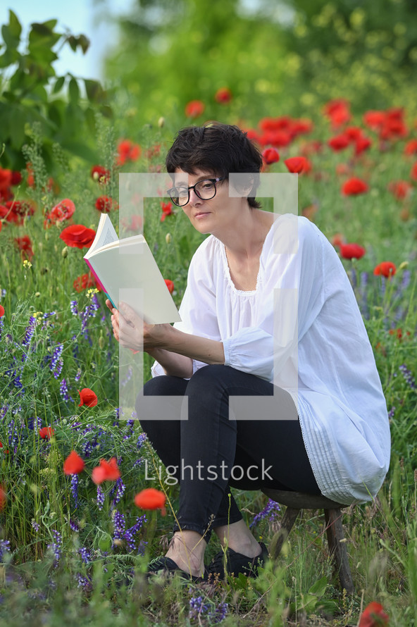 a woman reading in a meadow of poppies 