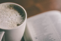 Cup of coffee and open Bible on a table.
