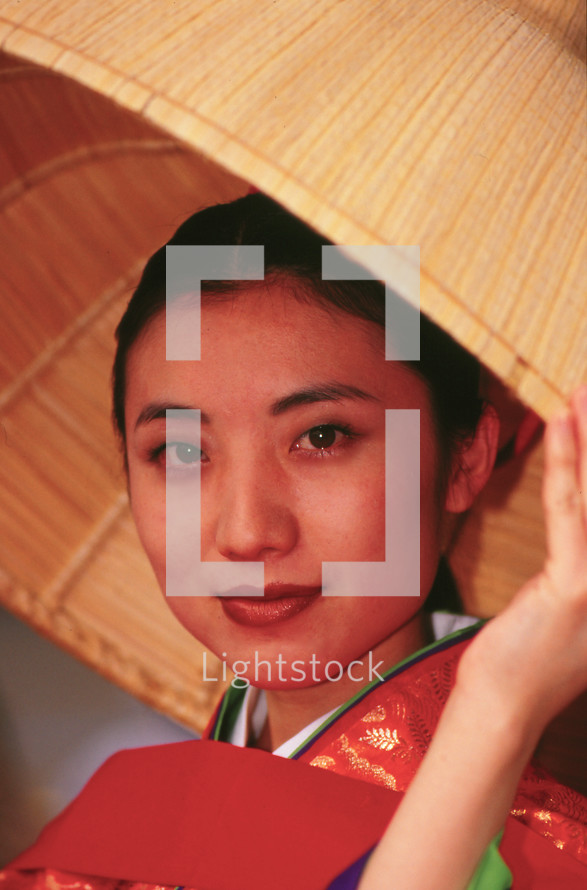 Japanese woman in kimono under a straw hat 