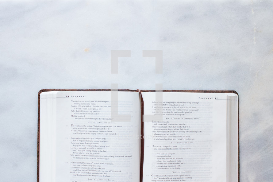 A Bible on marble countertop open to Proverbs 