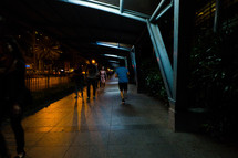 pedestrians walking on a sidewalk at night 