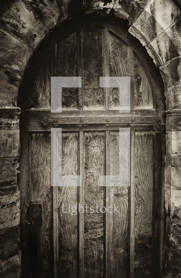Arched wooden doorway in an ancient stone cathedral.