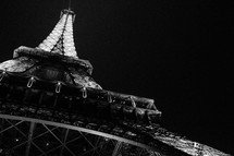 looking up to the top of the Eiffel Tower at night 