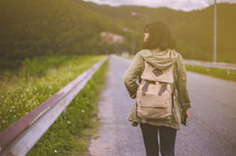 a woman walking alone down a road carrying a Bible 