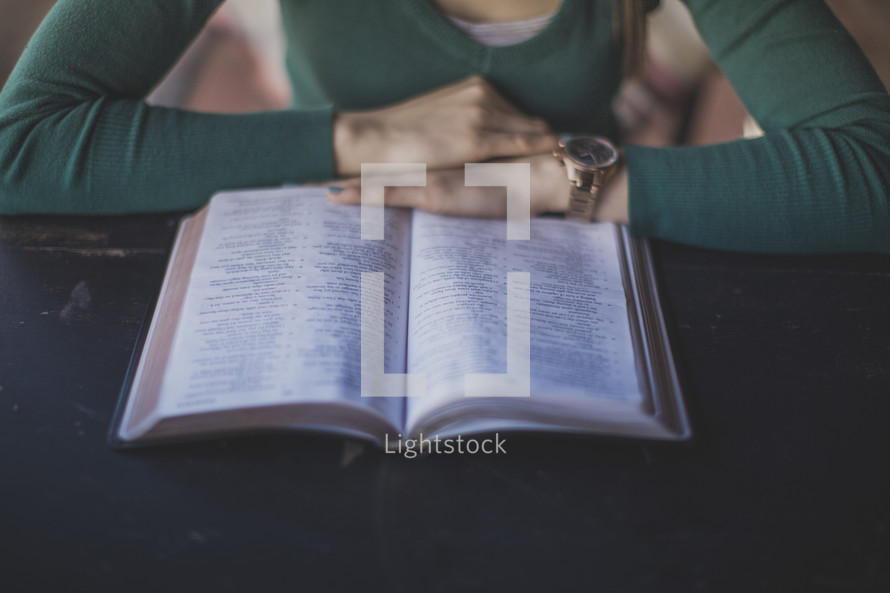 A woman sitting at a table and reading the Bible