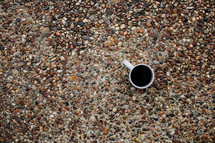 coffee mug on gravel sidewalk 