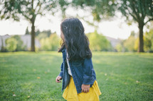 A little girl looking away in a field of grass.