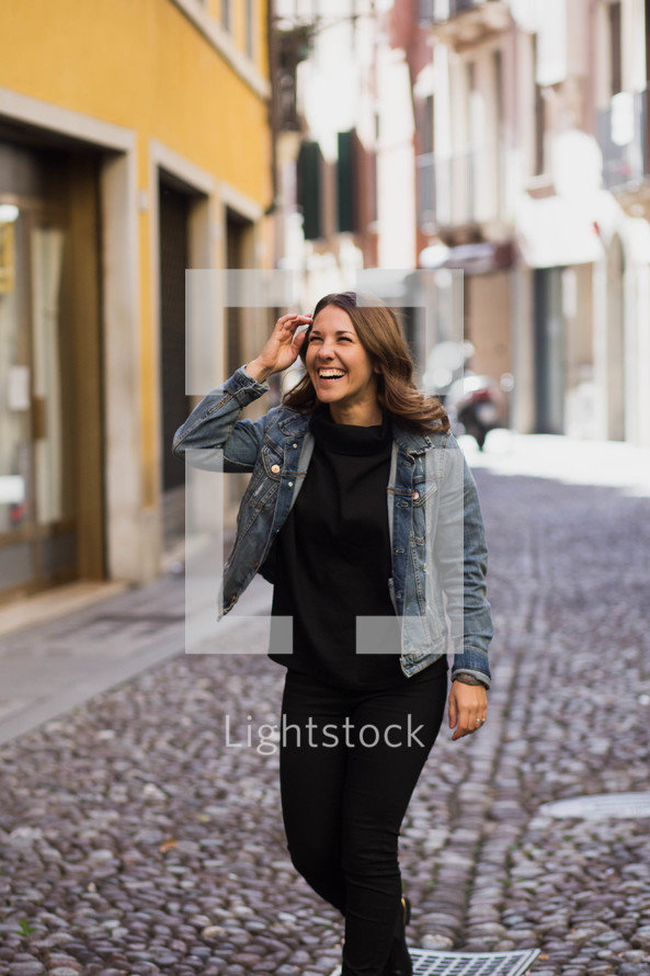 a woman standing in the middle of a cobblestone street 