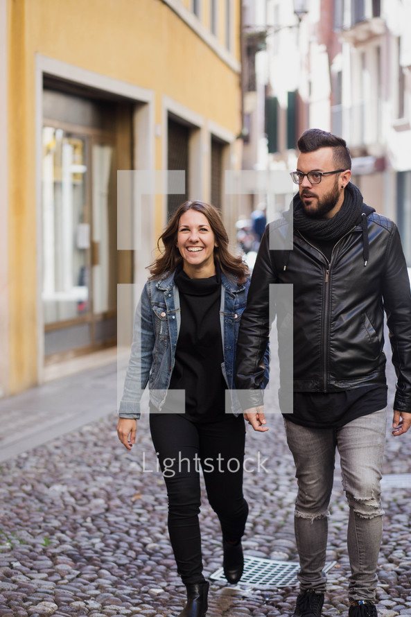 couple walking holding hands on a cobble stone street 