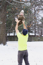 father and infant outdoors in snow 