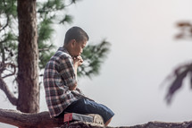 a boy sitting in a tree praying 