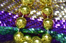 Festive Fat Tuesday beads on traditional Mardi Gras Purple, Gold, and, Green stripes 