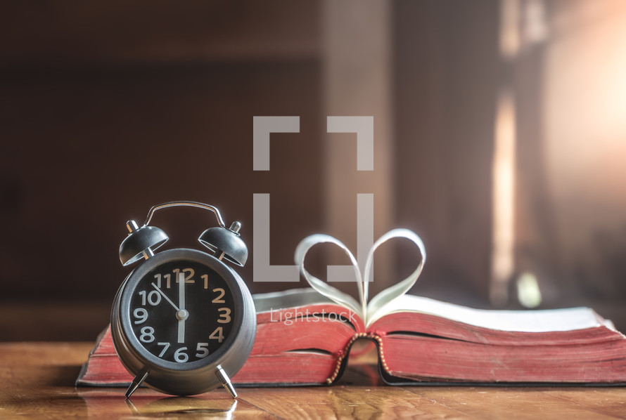Alarm clock and Holy bible on wood table in the morning