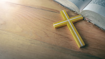wooden cross and open Bible on a wood table 