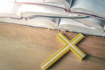 yellow cross on a wood background and open Bible 