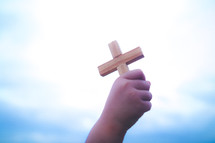 Hand holding a wooden cross up to the sky