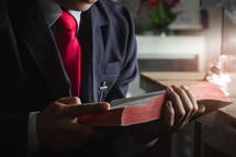 a man in a suit reading a Bible 