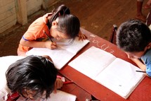 children studying at a table in a classroom 