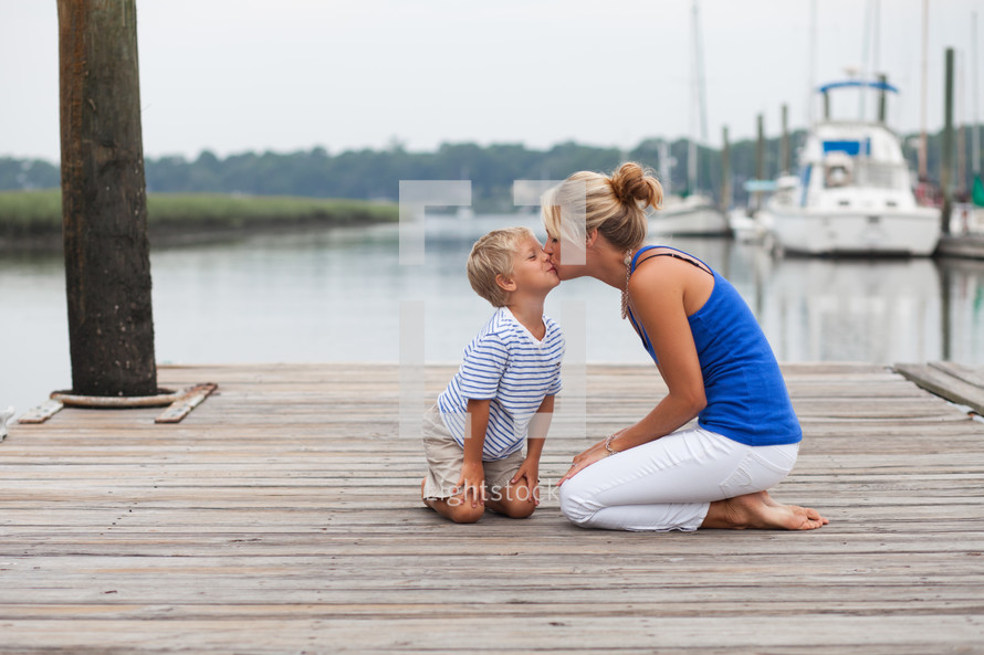 mother kissing her son on a dock 