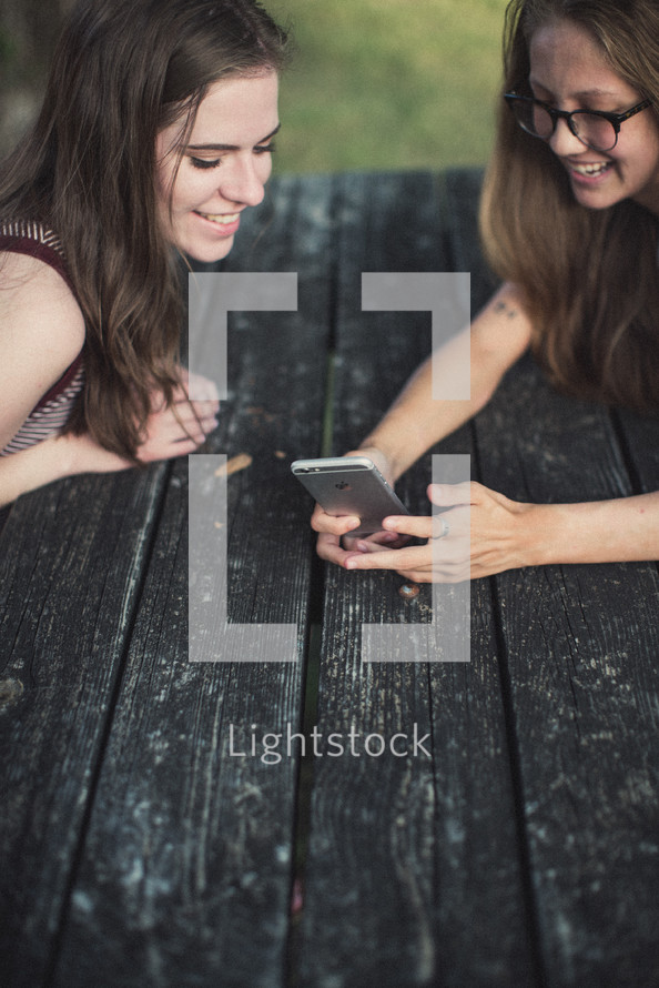 teen girls looking at a cellphone screen 