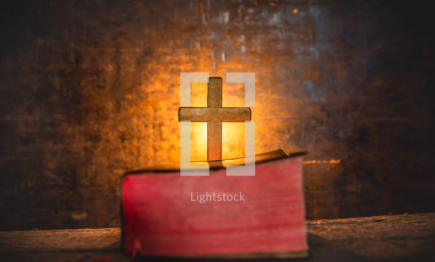glowing cross in front of a closed Bible 