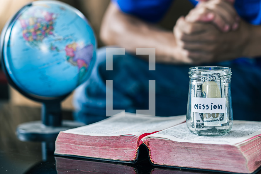 Savings jars full of money with passport and bible for mission, christian concept