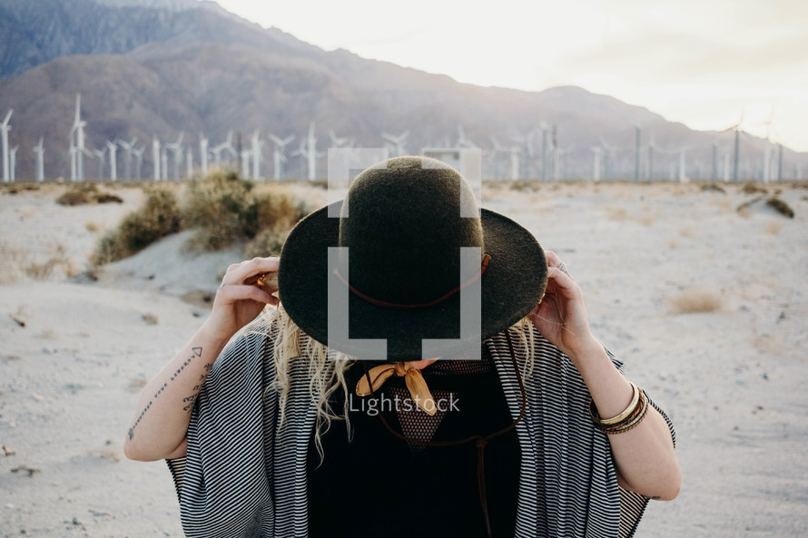 a woman standing in a desert and view of wind turbines 