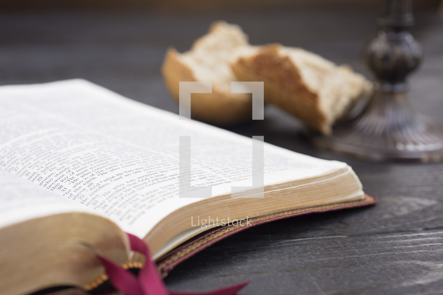 an open Bible, bread, and chalice for communion 