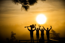 silhouettes of four Christian young men at sunset 