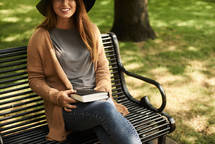 a woman sitting on a park bench holding a Bible 