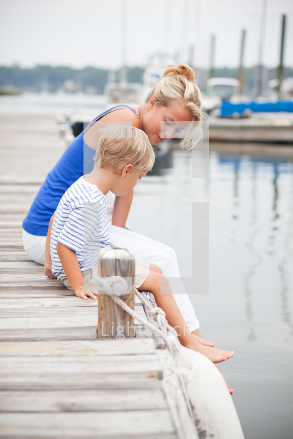 mother and son sitting at the edge of a dock 