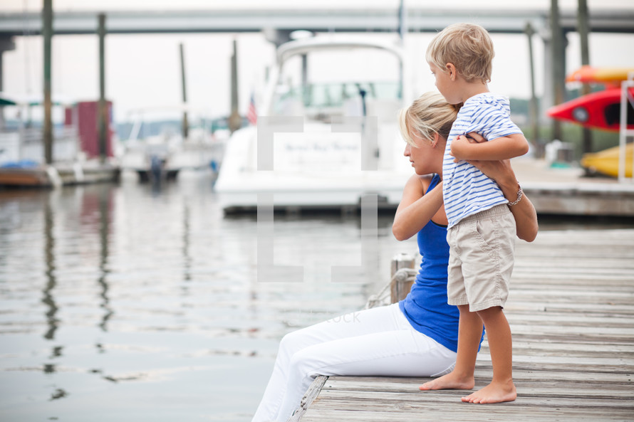 mother and son sitting on a dock 