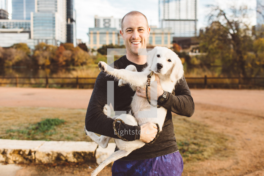 a man holding a puppy 