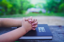 Hands of child girl praying on bible with pray with faith, christian concept.