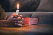 praying hands and Bible with candle 