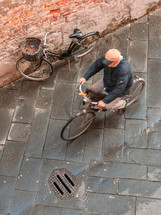 man riding a bike on a cobblestone street 