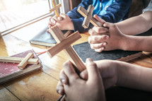 small group Bible study praying holding wooden crosses 