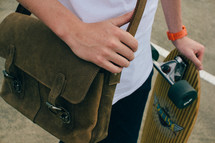 man with a leather satchel and skateboard 