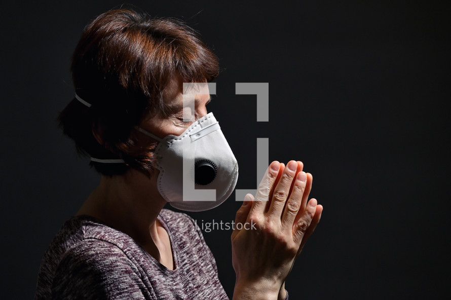Woman Wearing Medical Protective Virus Mask and pray on dark background