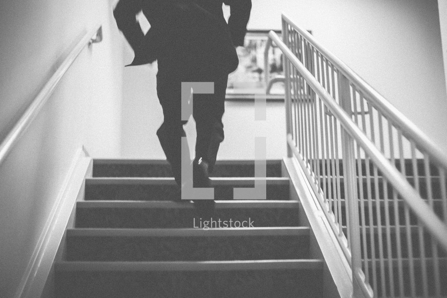 A man running up stairs in a tuxedo 