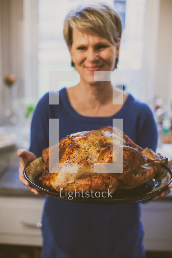 a woman holding a roasted turkey 
