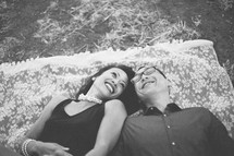happy couple lying on a blanket in the grass 