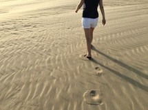 a woman walking over the sand 