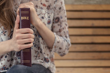 a young woman holding a Bible praying 