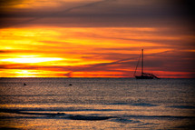Sunset with boat sailing on the ocean.
