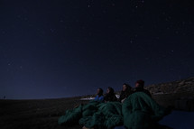 campers in sleeping bags looking up at the night sky
