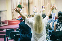 Woman worshiping God with hands up, at church