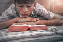 a man reading a Bible in bed 